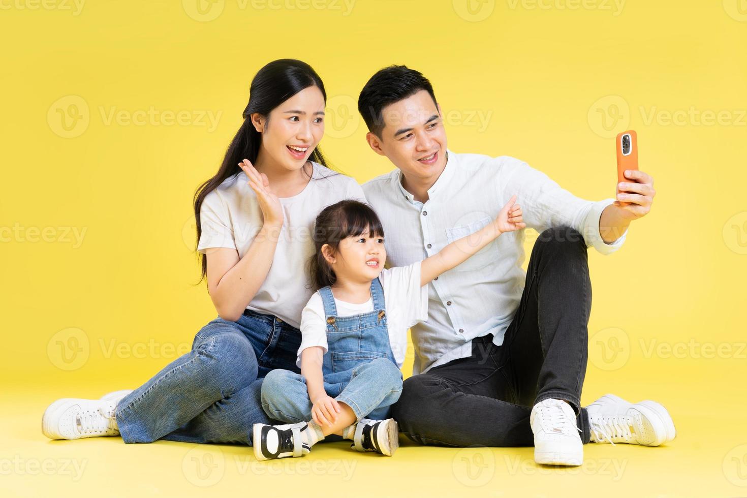 imagem da família asiática sentados juntos felizes e isolados em fundo amarelo foto