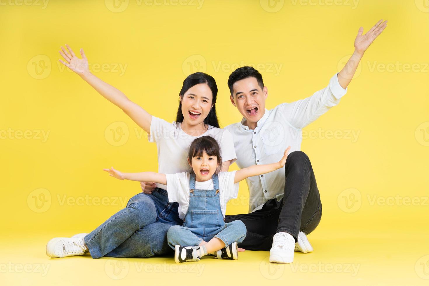 imagem da família asiática sentados juntos felizes e isolados em fundo amarelo foto