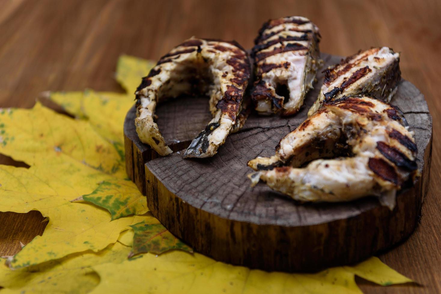 bifes de peixe fritos na grelha deitado no tronco de uma árvore foto