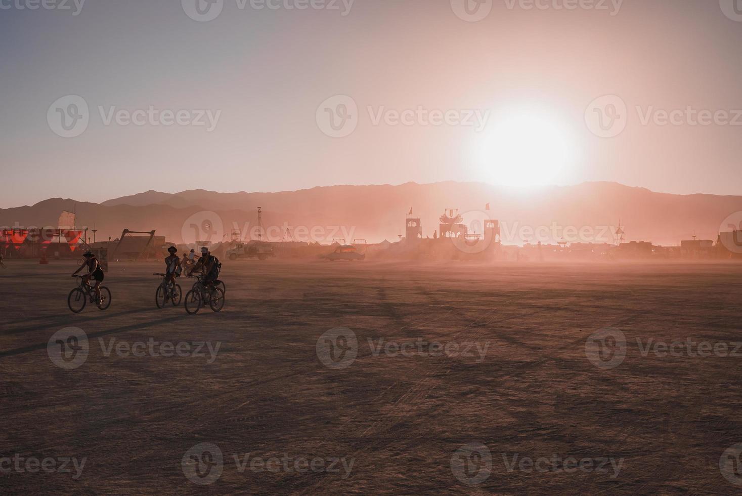 pessoas caminhando para pôr do sol às uma festival dentro a deserto às a queimando homem festival. foto