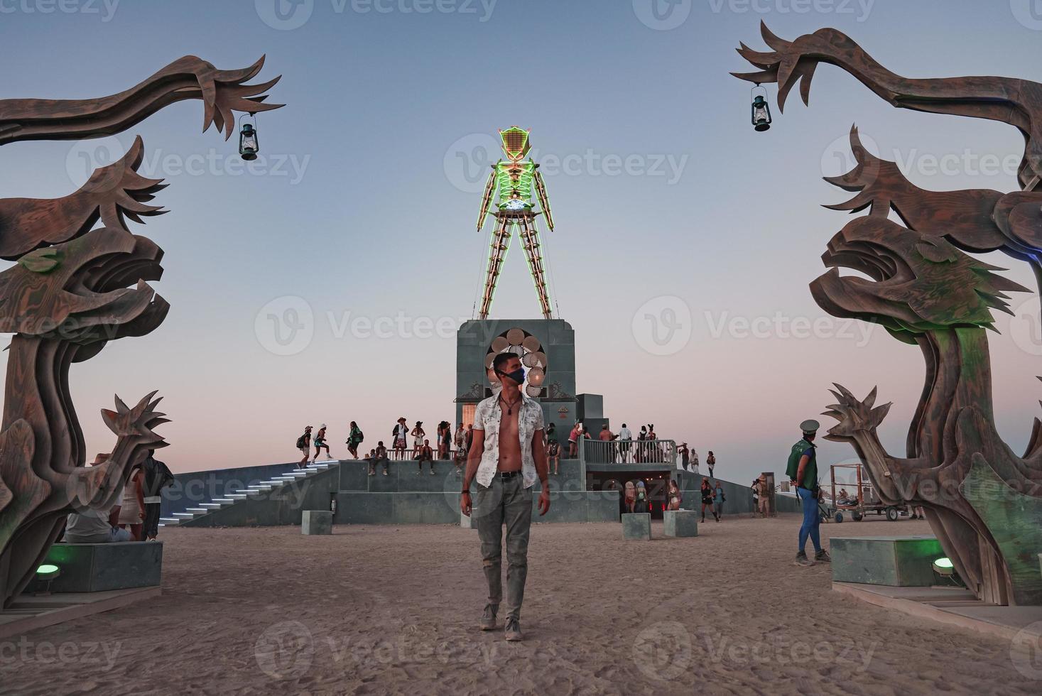 pessoas caminhando para pôr do sol às uma festival dentro a deserto às a queimando homem festival. foto