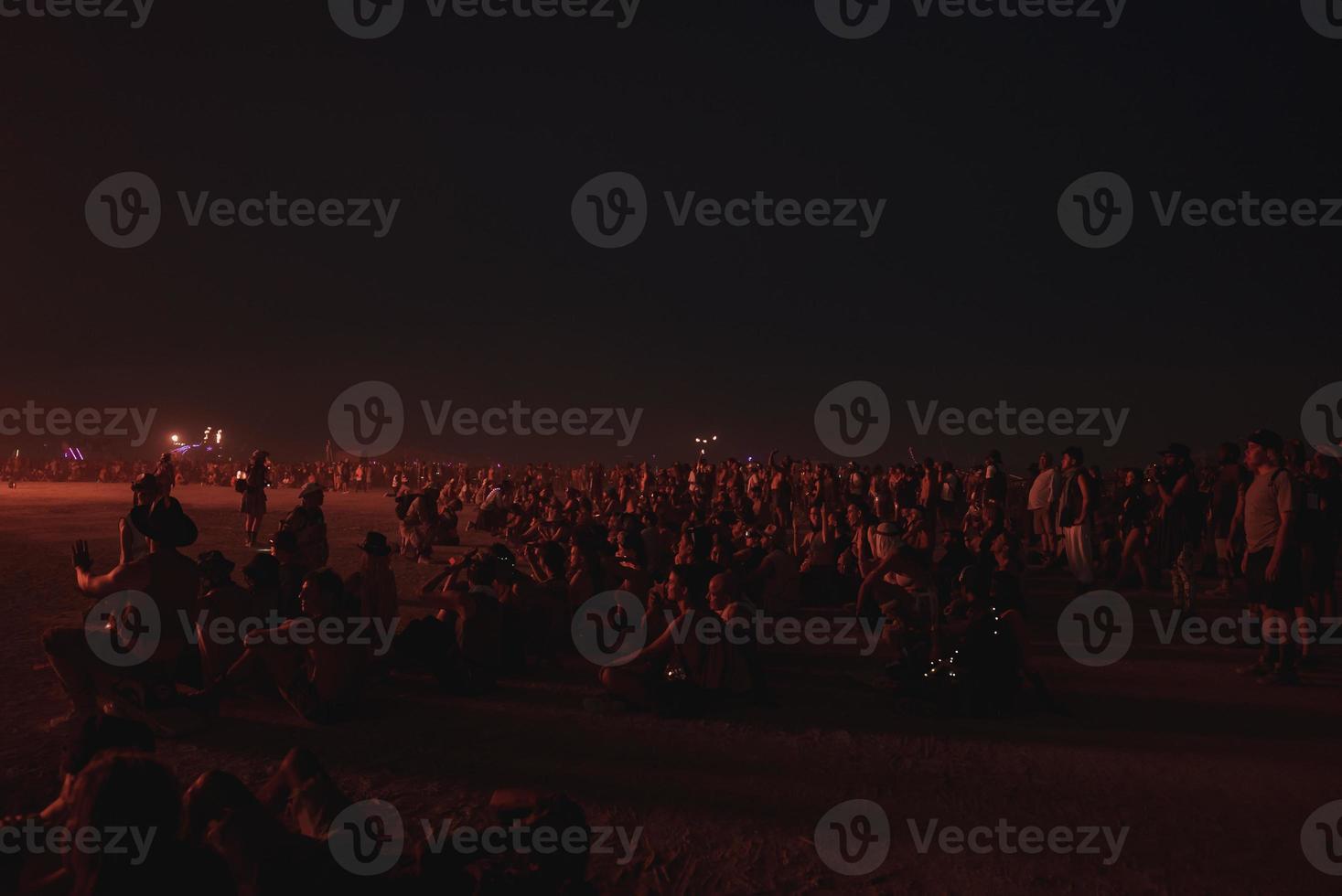 pessoas caminhando para pôr do sol às uma festival dentro a deserto às a queimando homem festival. foto