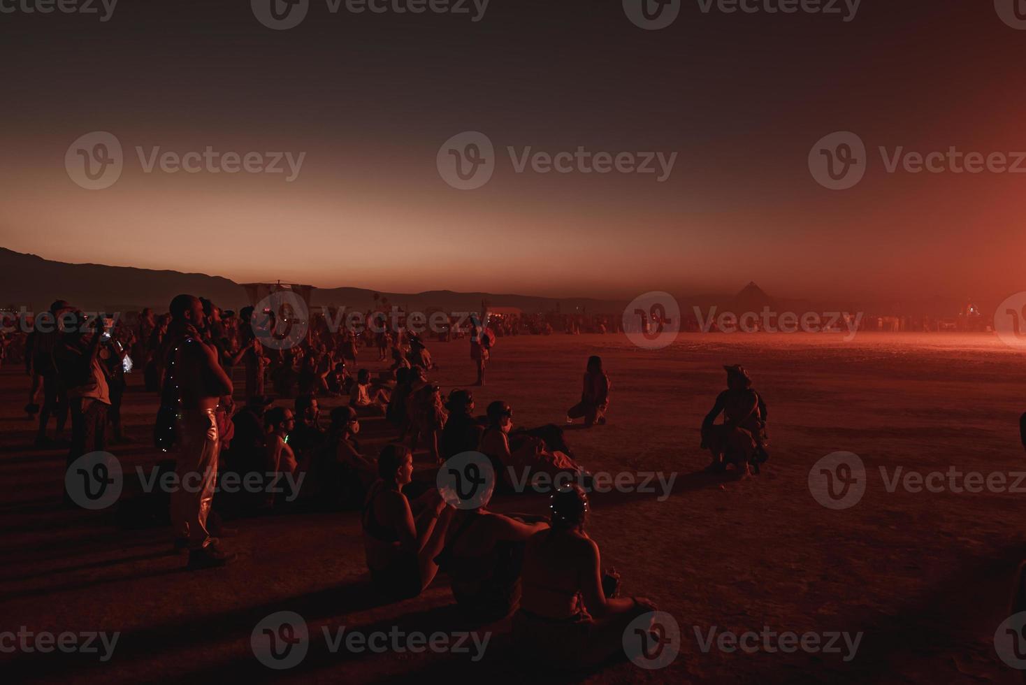 pessoas caminhando para pôr do sol às uma festival dentro a deserto às a queimando homem festival. foto