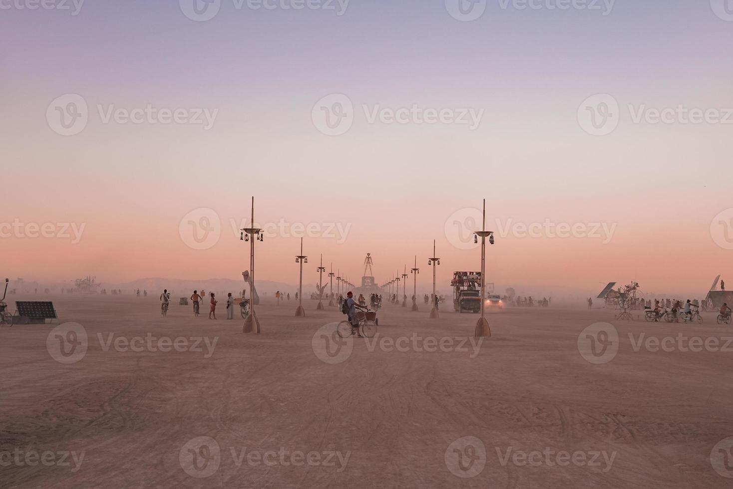 pessoas caminhando para pôr do sol às uma festival dentro a deserto às a queimando homem festival. foto