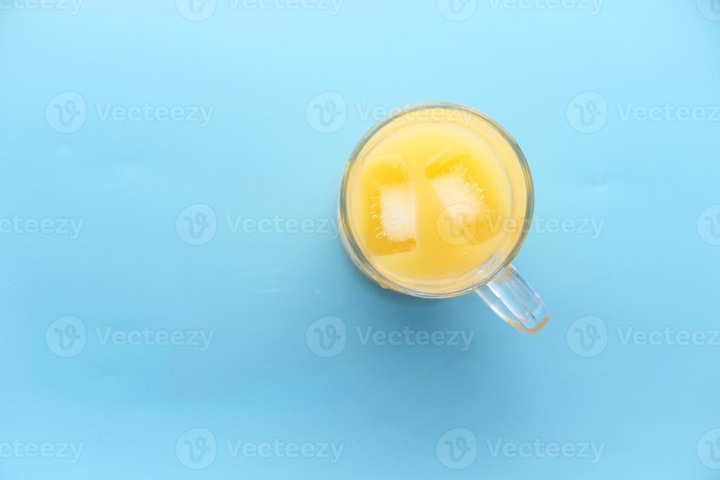 suco de laranja com gelo no fundo azul foto