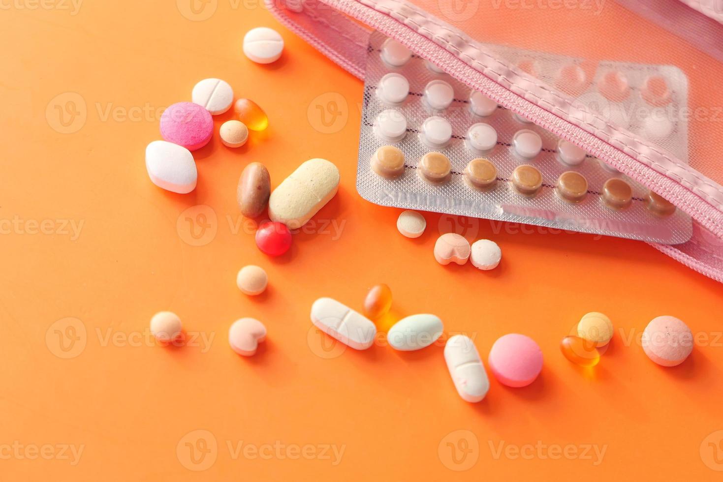pílulas anticoncepcionais em fundo laranja foto