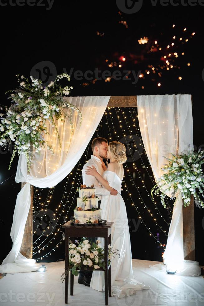 noivos alegremente cortam e provam o bolo de casamento foto