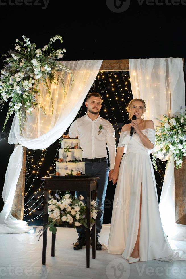 noivos alegremente cortam e provam o bolo de casamento foto