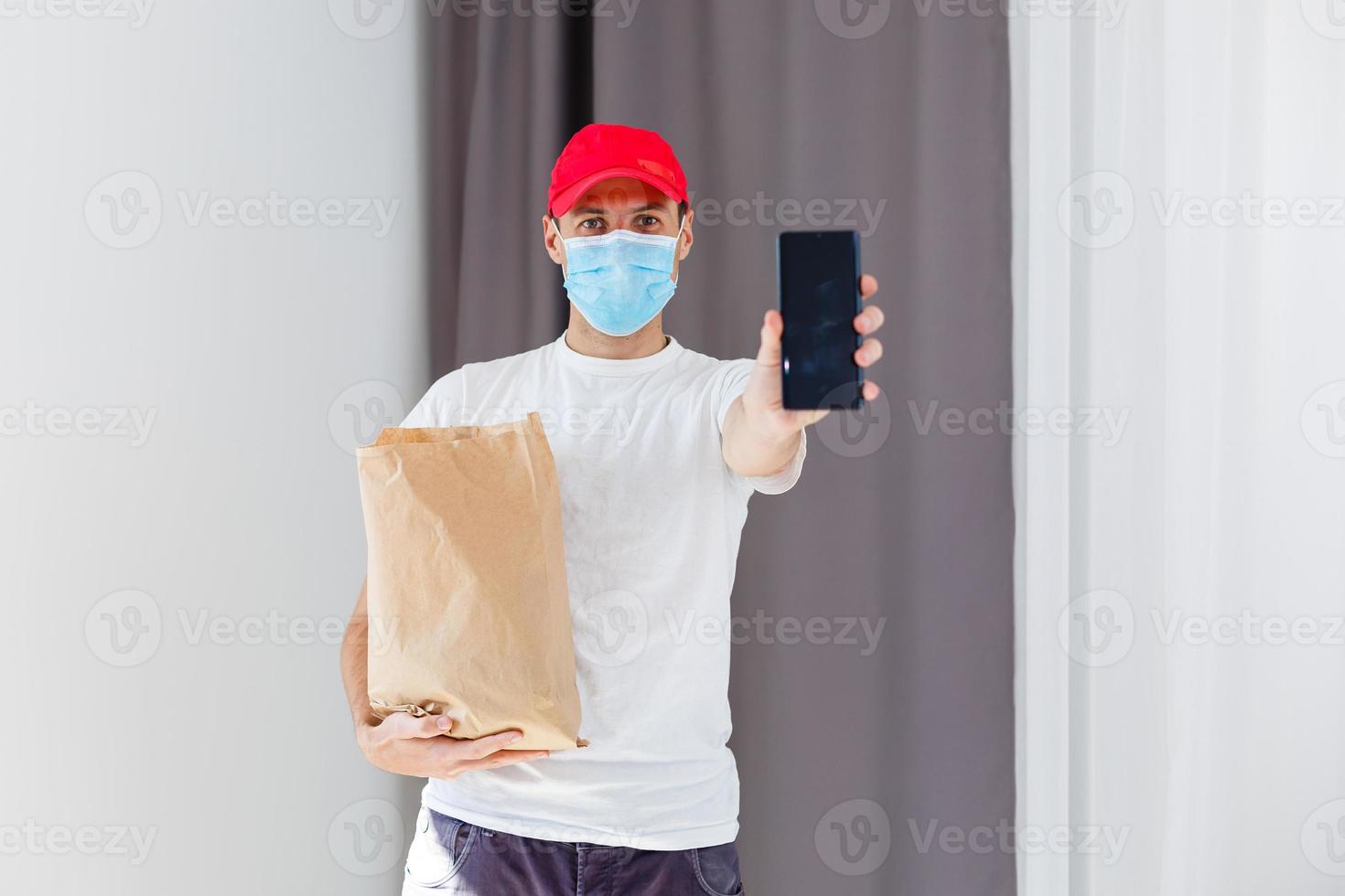 Entrega homem segurando papel saco com Comida em branco fundo, Comida Entrega homem dentro protetora mascarar foto