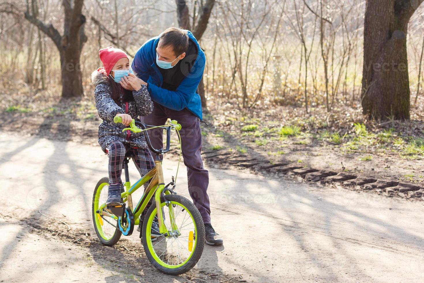 caucasiano pai ajudando filha passeio bicicleta vestindo proteção mascarar para proteger pm2.5 e coronavírus covid-19 pandemia vírus sintomas. foto