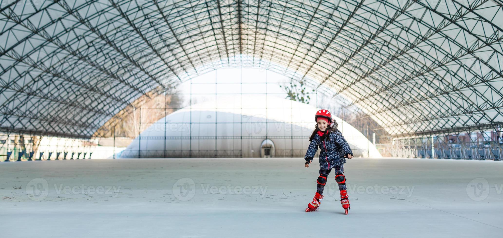 pequeno fofa feliz menina patins dentro uma grande hangar foto