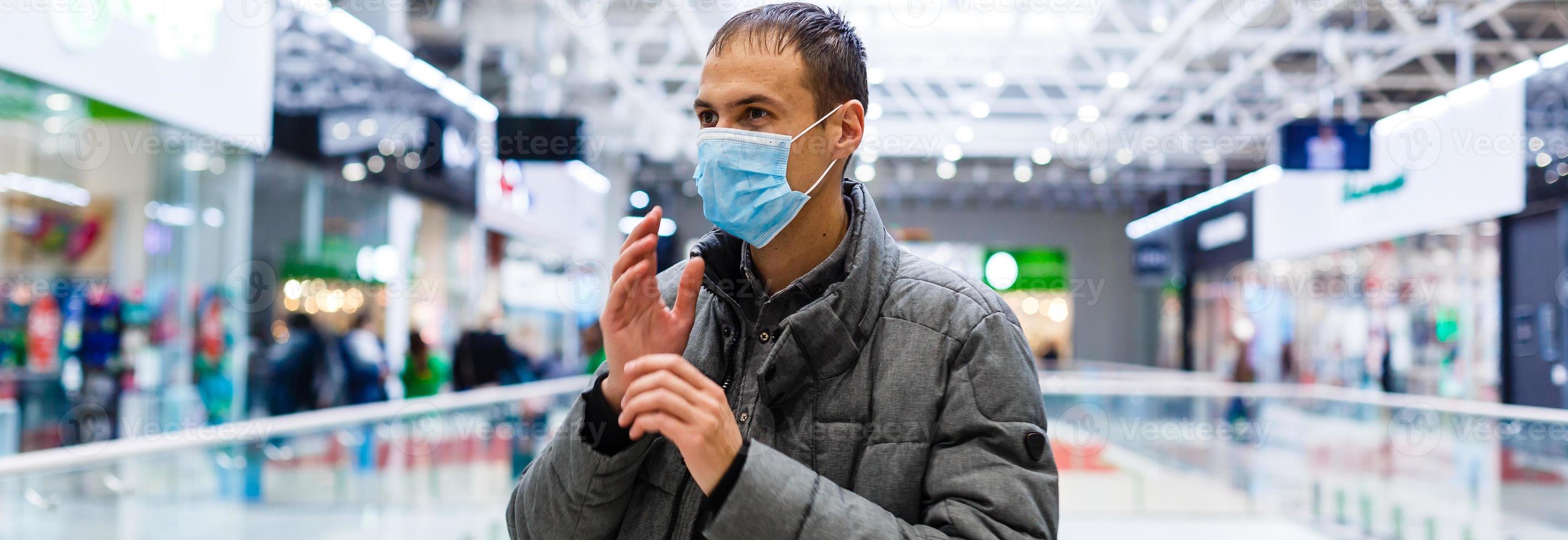 uma jovem homem dentro uma médico mascarar dentro uma compras Centro. a mascarado homem protege ele mesmo a partir de a epidemia do a chinês vírus 2019 foto