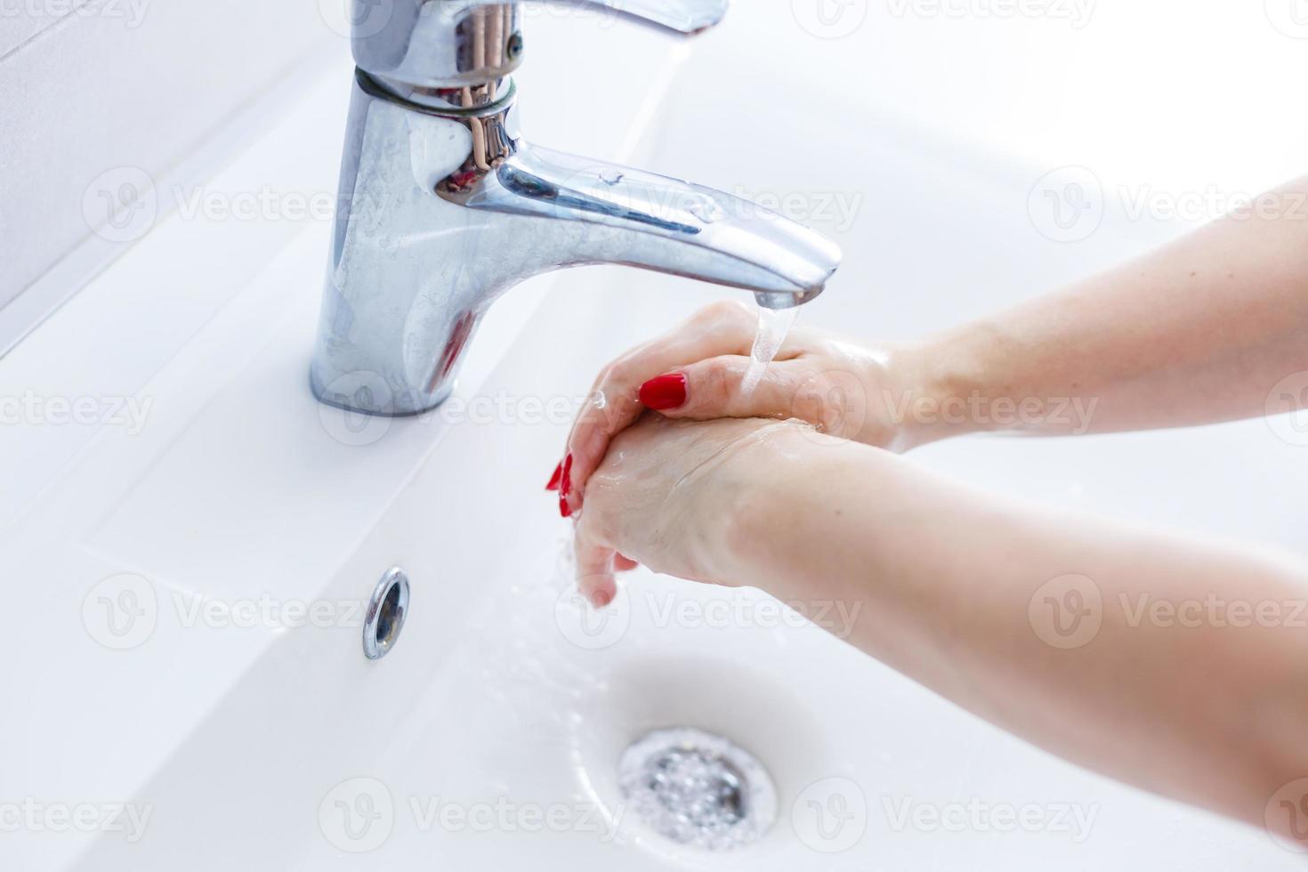 lavando mulher mãos com transmissão água debaixo toque dentro banheiro,lavar mãos dentro uma branco bacia com uma bar, higiene, mão lavando, mulher lavando mãos debaixo uma toque água foto