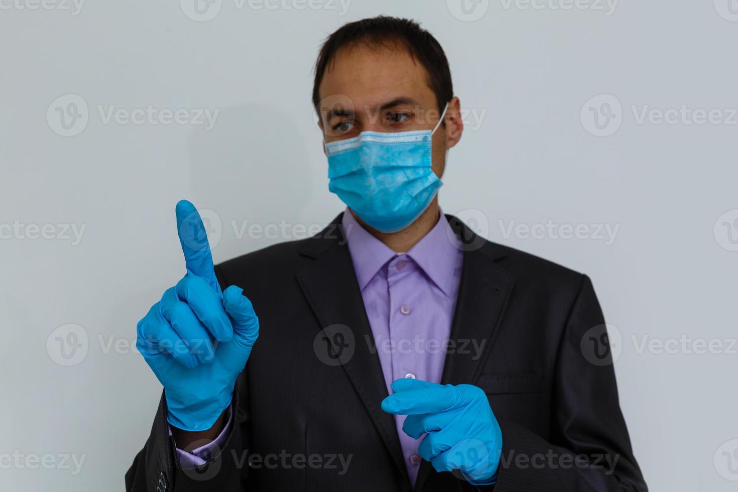 fechar acima do uma homem de negocios dentro uma terno vestindo protetora face mascarar, pegue pronto para coronavírus e PM 2,5 brigando contra cinzento fundo. cuidados de saúde conceito. foto