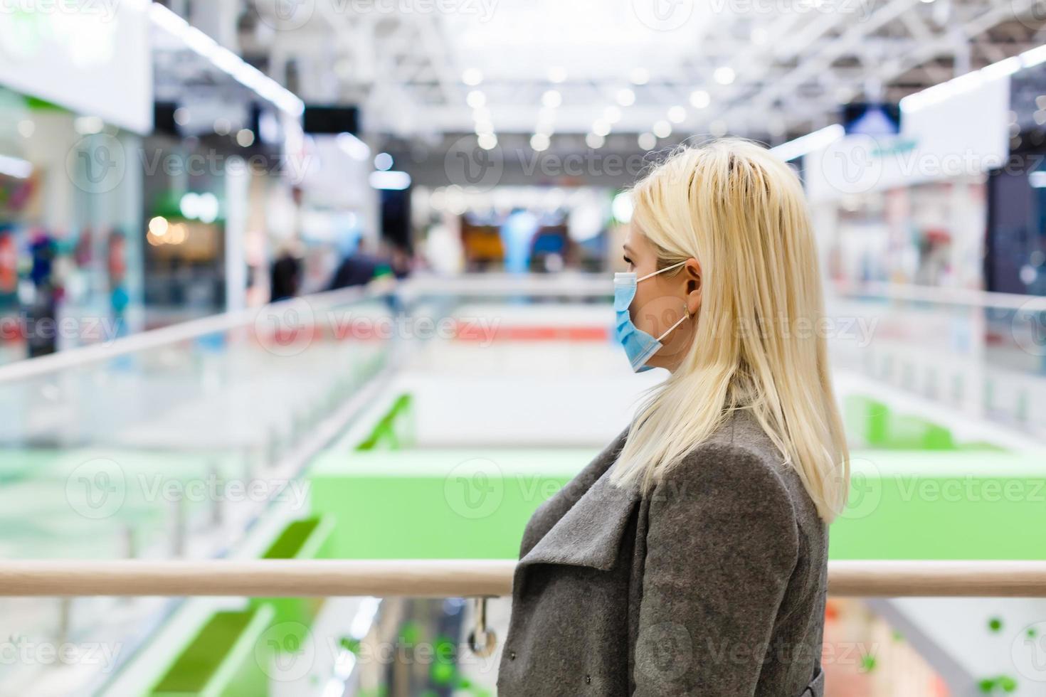 uma jovem mulher desgasta uma protetora mascarar enquanto compras às a shopping center. a conceito do doença saúde e vírus proteção. foto