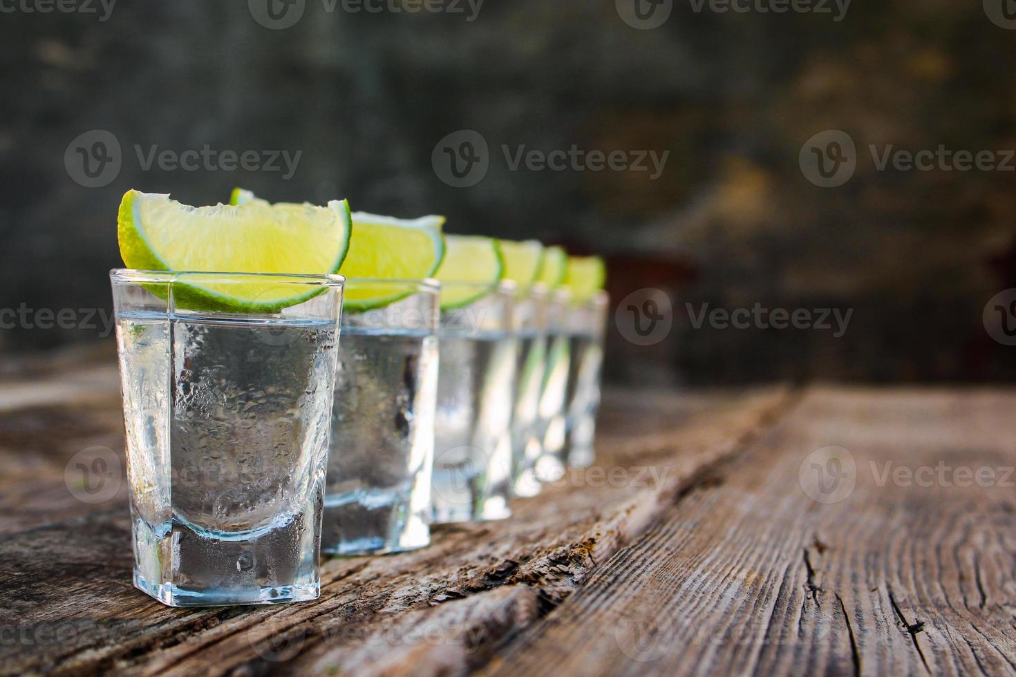 vodka e Lima fatias em de madeira fundo. foto