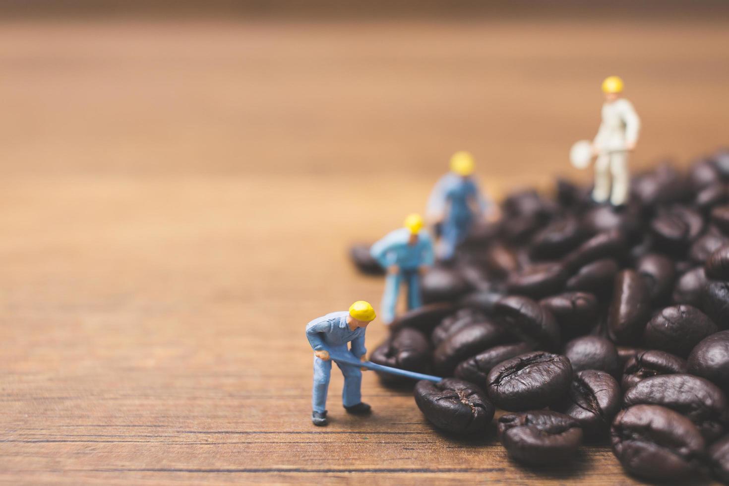 pessoas em miniatura trabalhando em grãos de café torrados foto