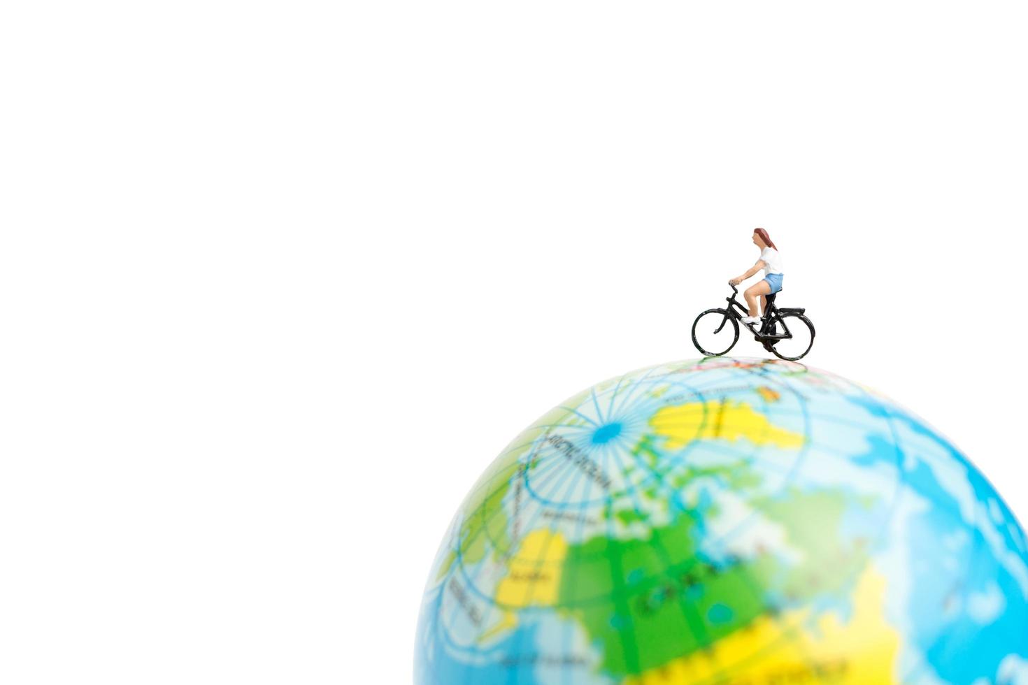 viajante em miniatura com uma bicicleta em um globo em um fundo branco foto