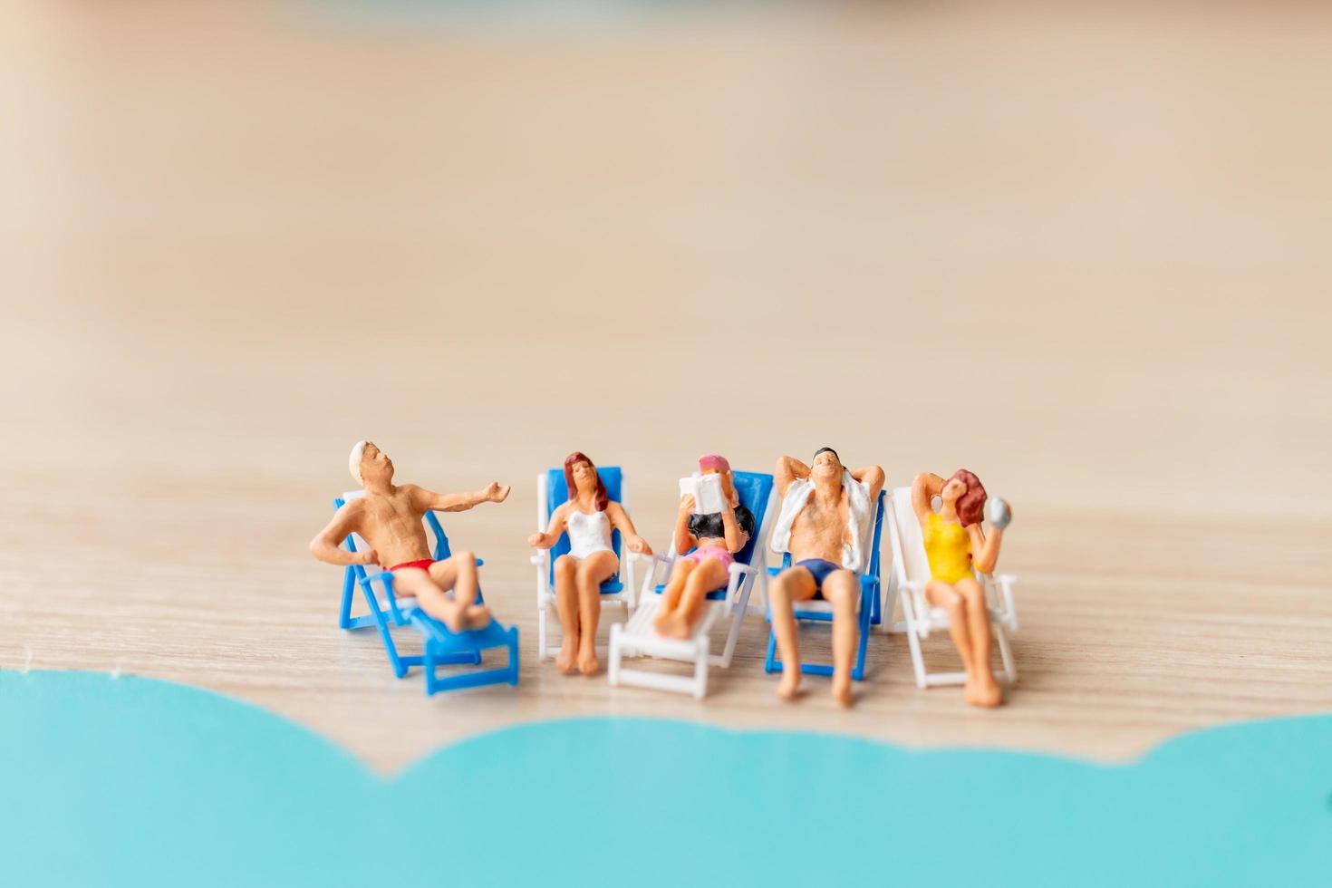 pessoas em miniatura tomando banho de sol na praia, conceito de verão foto