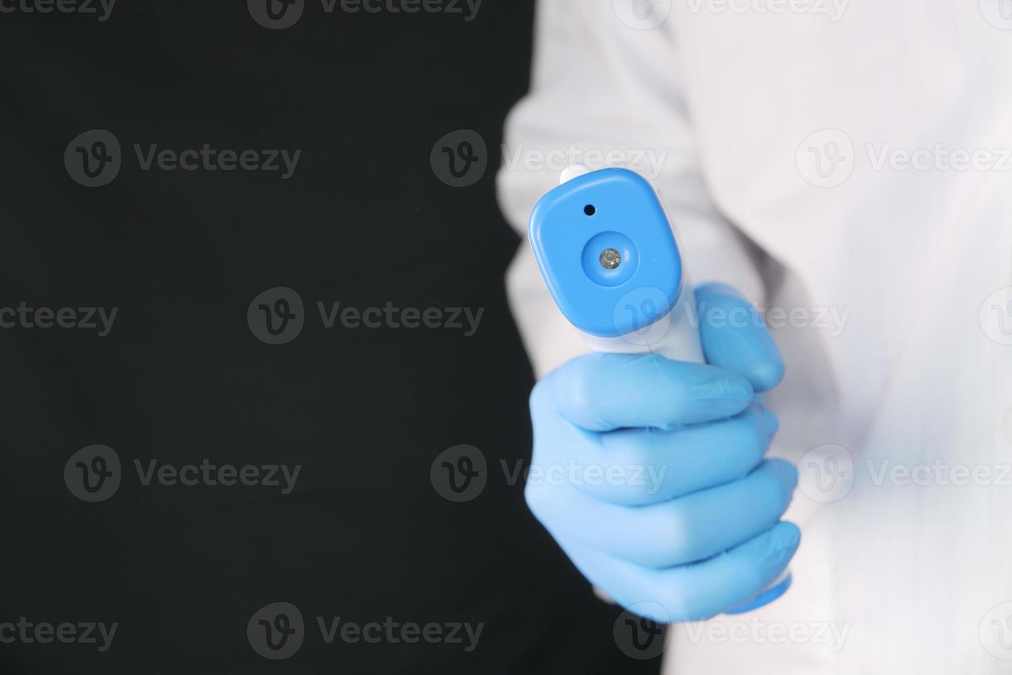 mão segurando termômetro infravermelho para medir a temperatura foto