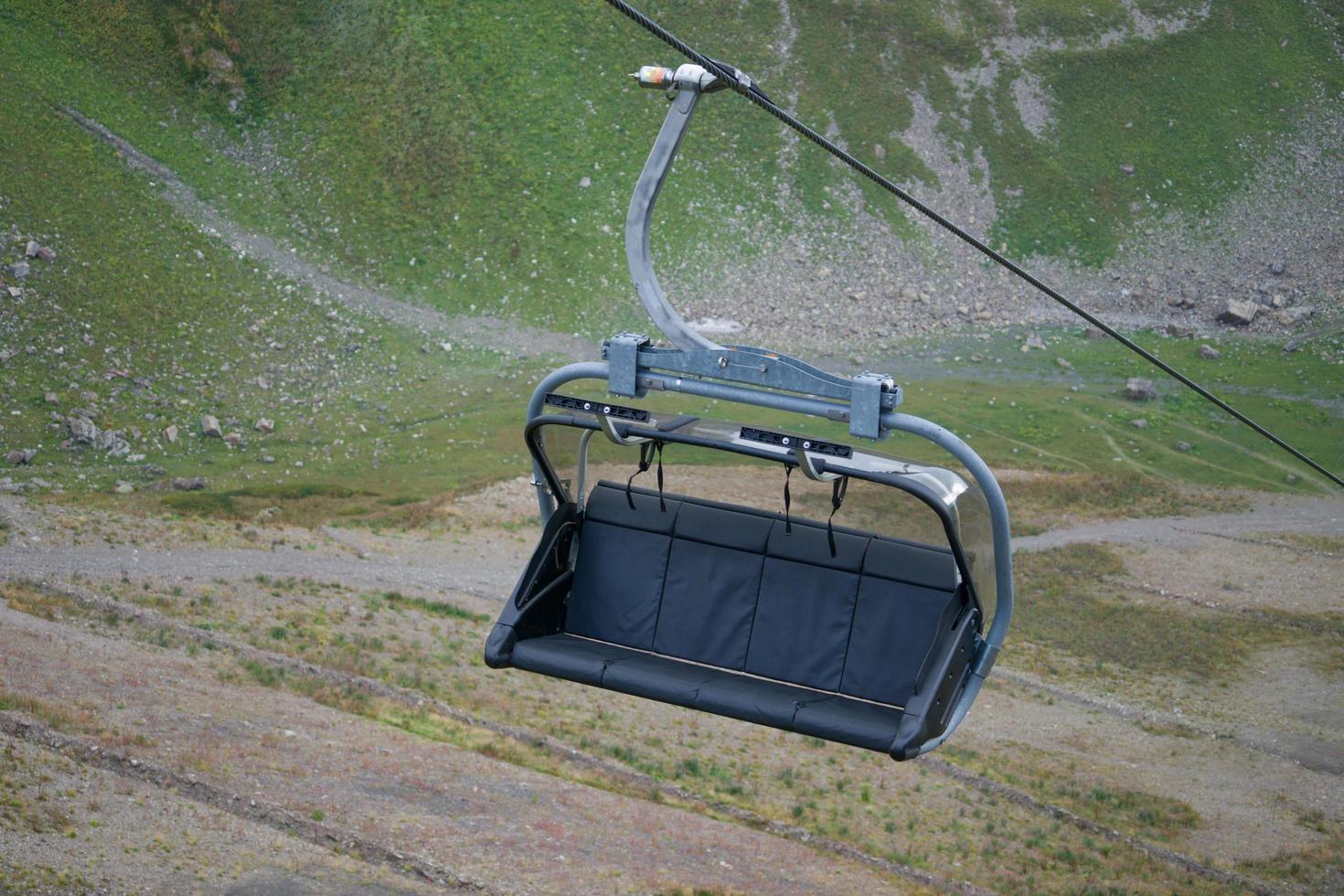 banco ou cadeira de teleférico em um cabo com uma montanha ao fundo foto