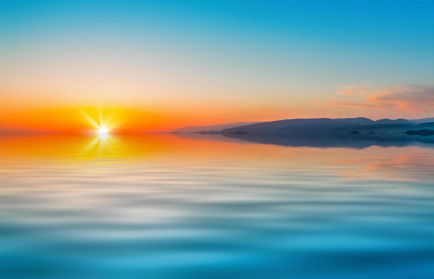 pôr do sol laranja colorido e montanhas ao lado de um mar calmo foto