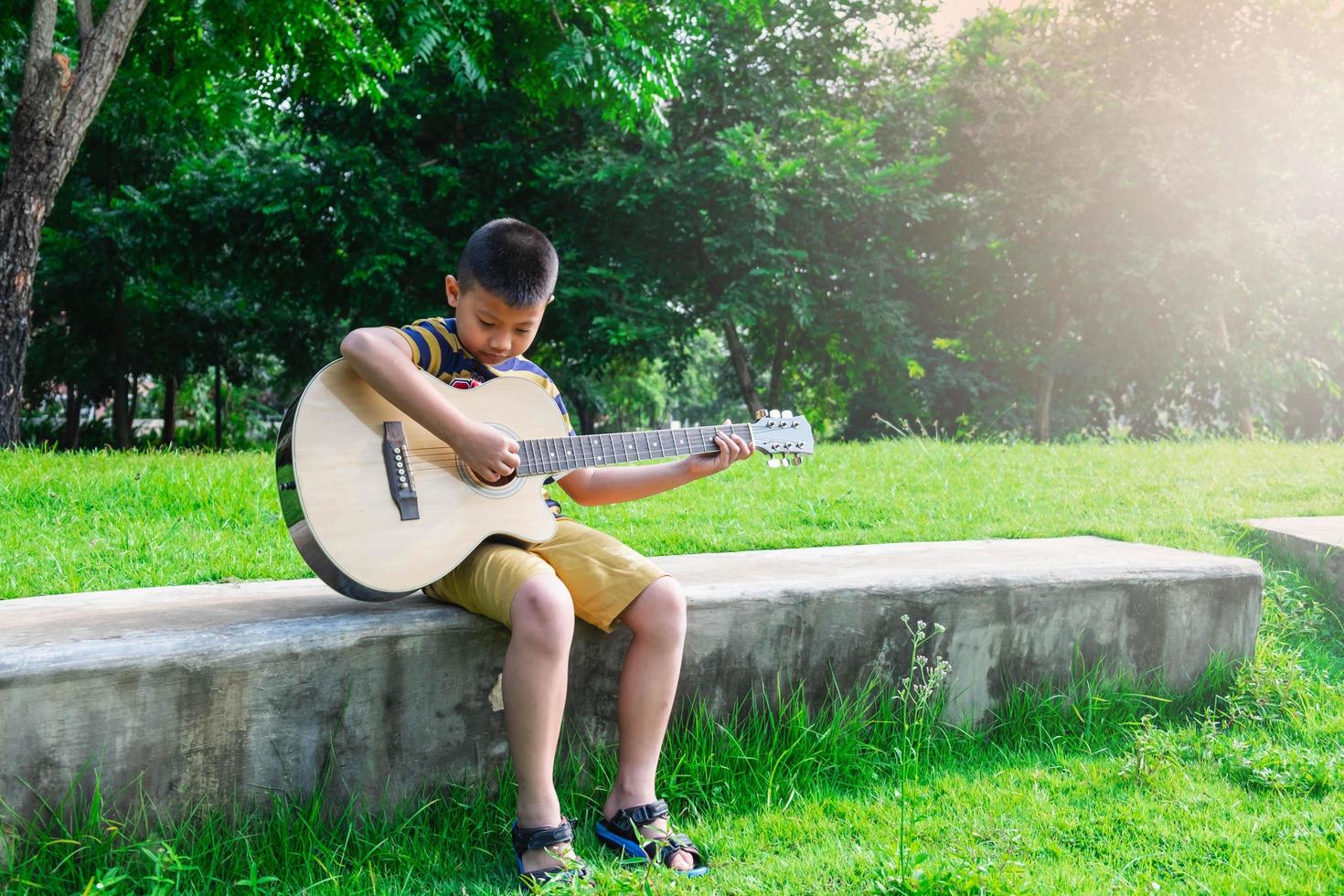 menino tocando violão em um jardim foto