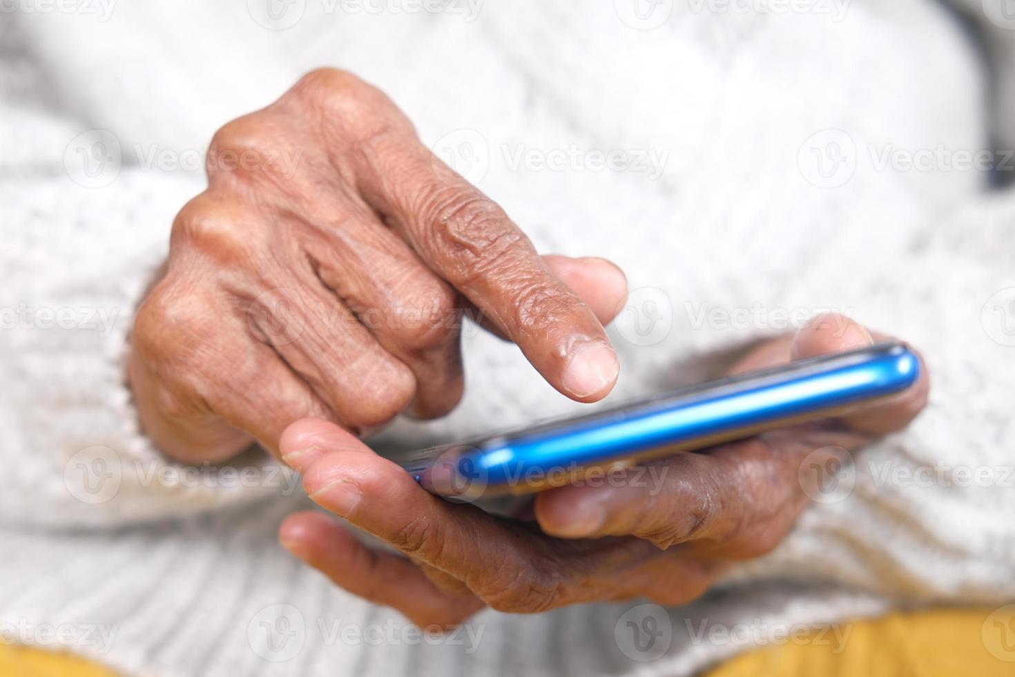 mão de uma mulher sênior usando telefone inteligente close-up foto