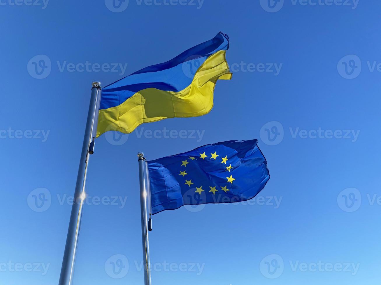 acenou ucraniano e europeu União bandeiras em mastros de bandeira contra azul céu foto