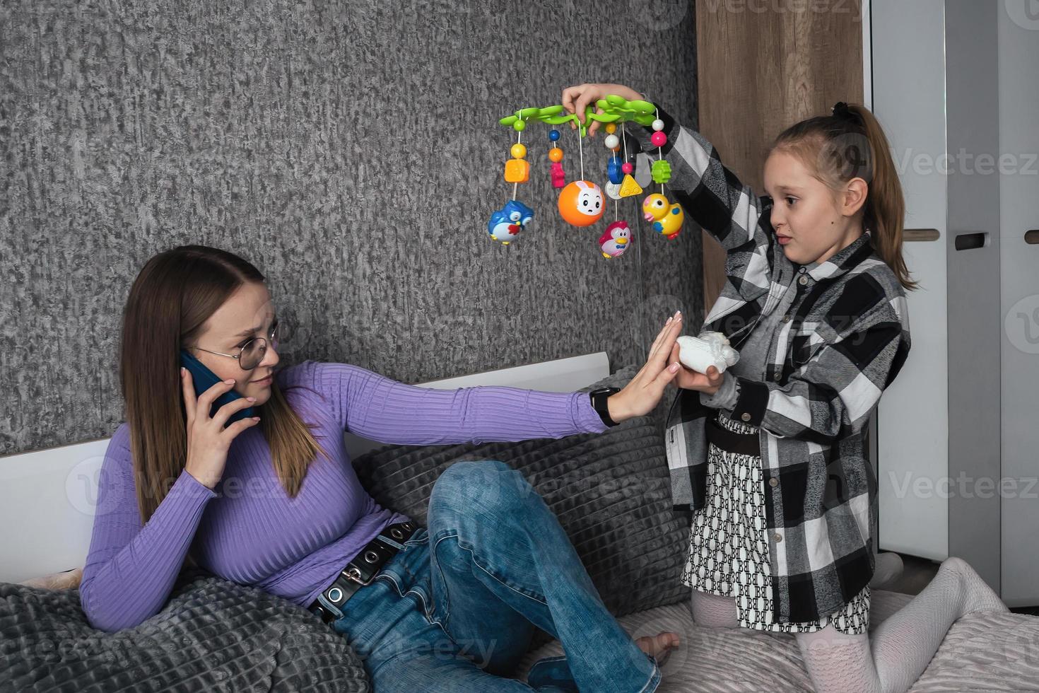 a menina pergunta dela mãe para dar nascimento para dela pequeno irmão ou irmã, a mãe é falando em a telefone e recusa dela filha. mulheres falta de vontade para ter crianças, 1 criança dentro a família foto