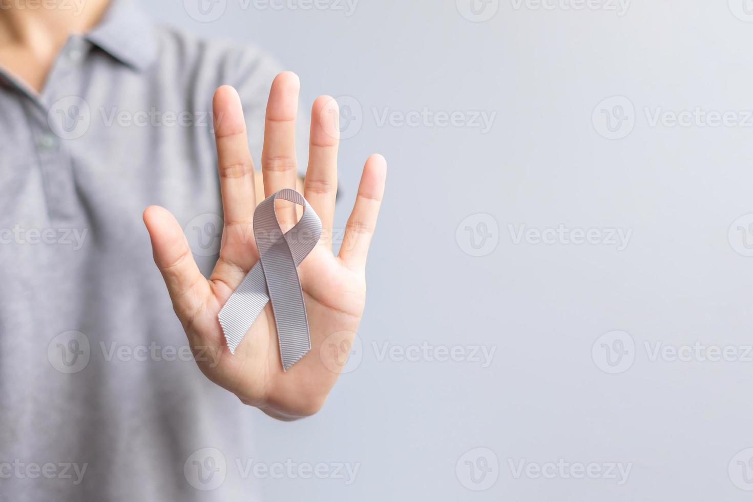 cérebro Câncer consciência mês, mulher mão segurando cinzento cor fita para apoiando pessoas vida. cuidados de saúde e mundo Câncer dia conceito foto