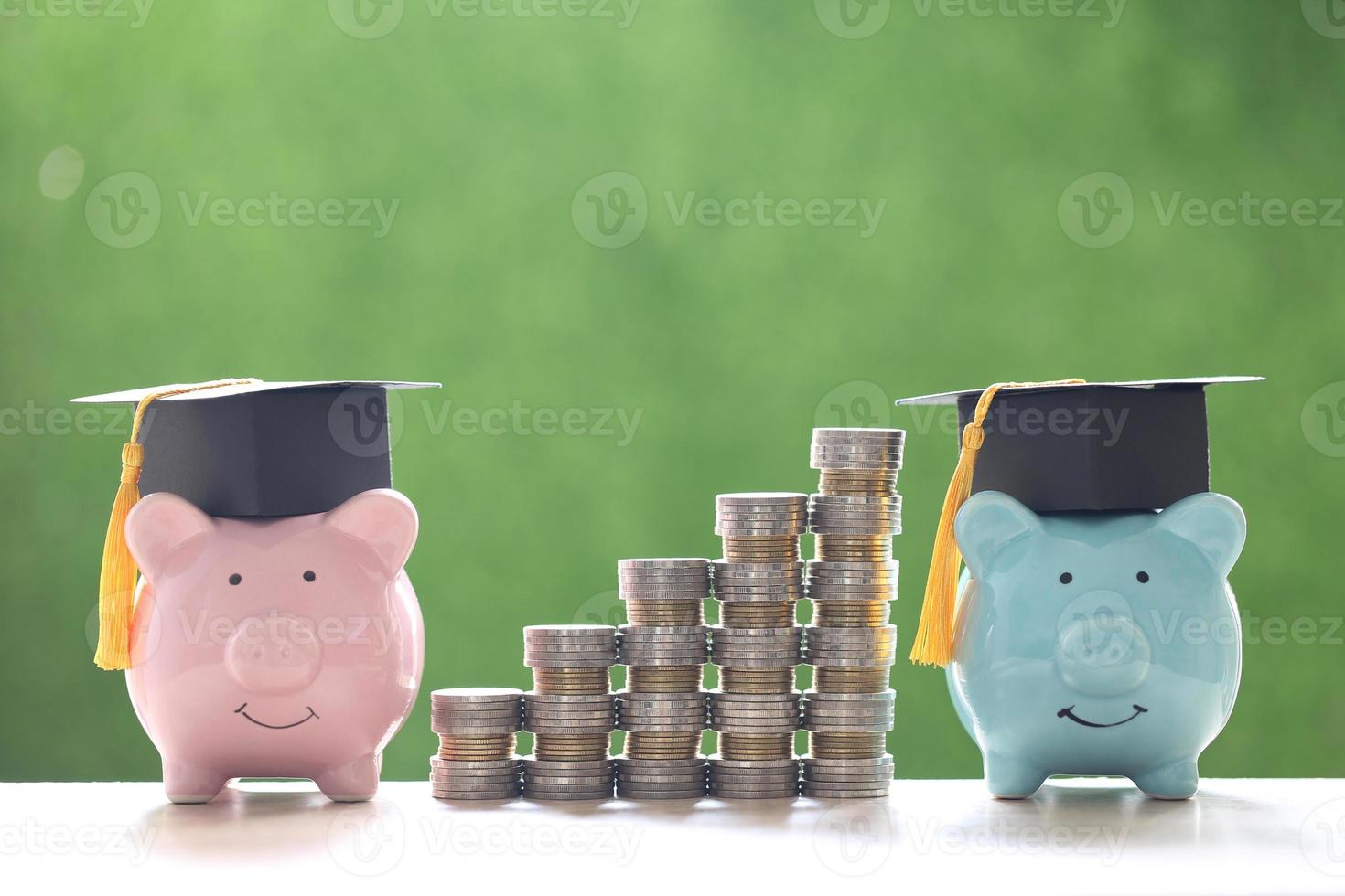 chapéus de formatura em cofrinhos e uma pilha de moedas em um fundo verde natural, economizando dinheiro para o conceito de educação foto