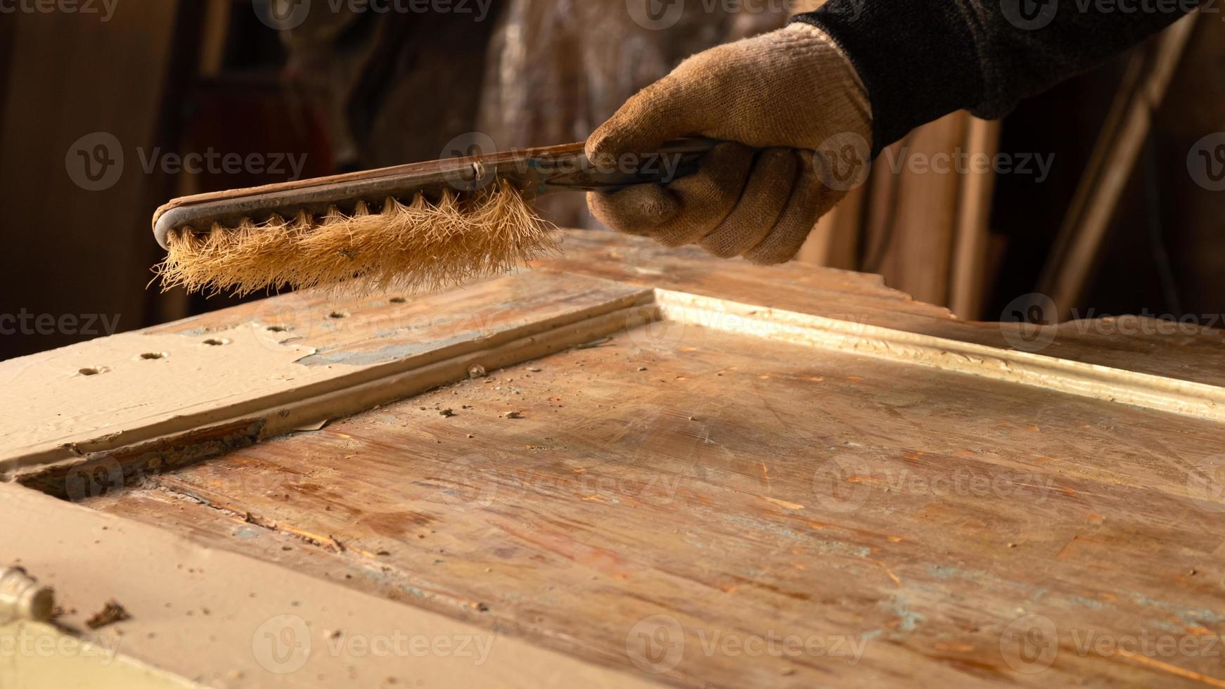 mãos limpando tinta velha de uma porta de madeira, restauração de móveis de madeira foto