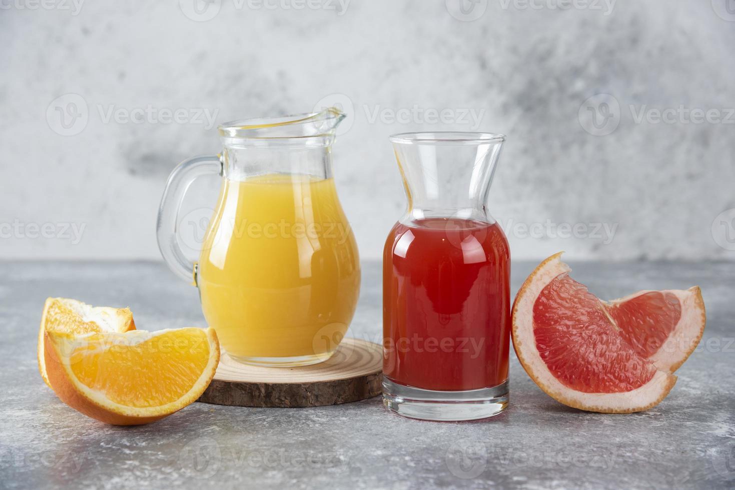 dois copos de toranja e suco de laranja em um fundo de pedra foto