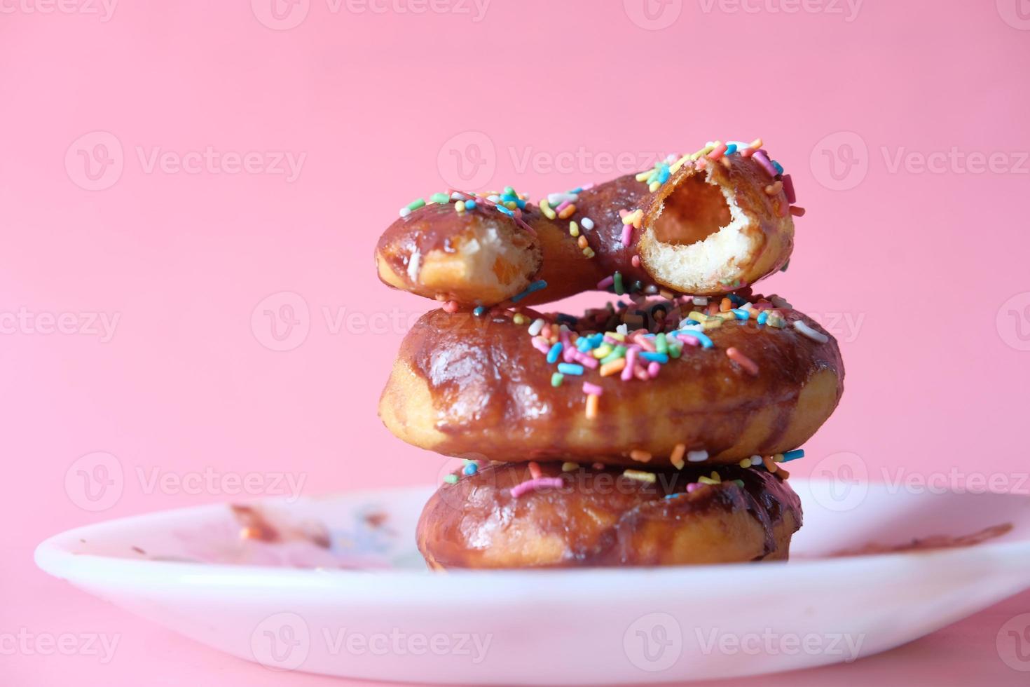 pilha de donuts de chocolate em fundo rosa foto