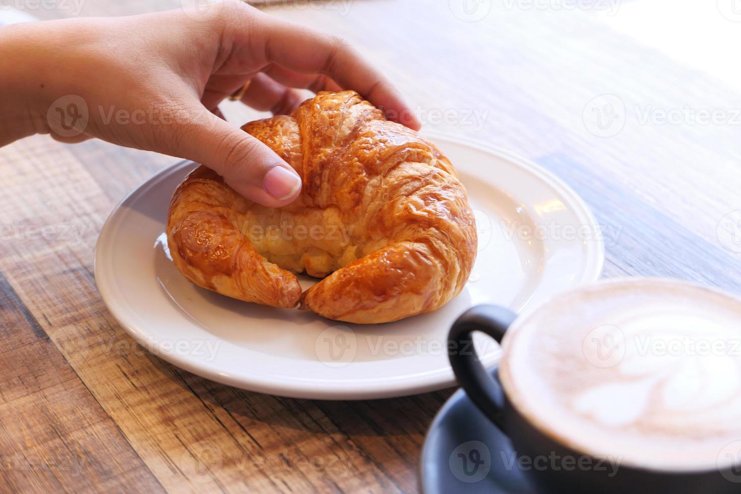 mão de mulher segurando um croissant foto