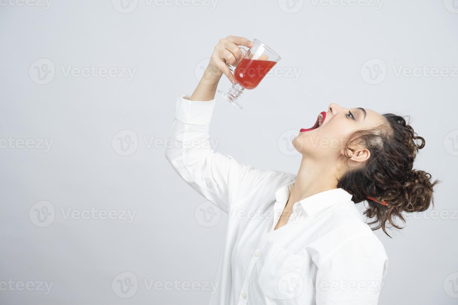 linda mulher em uma roupa branca bebendo um copo de suco vermelho foto