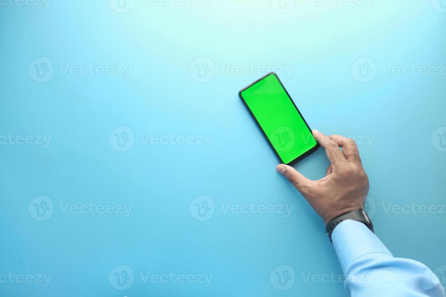 vista superior da mão segurando o telefone inteligente sobre fundo azul foto
