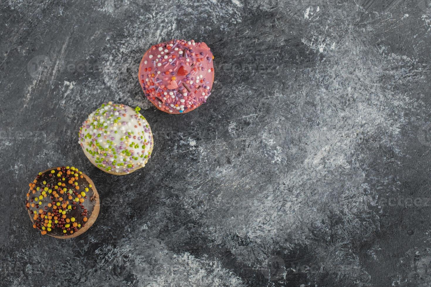 três rosquinhas doces coloridas com granulado foto