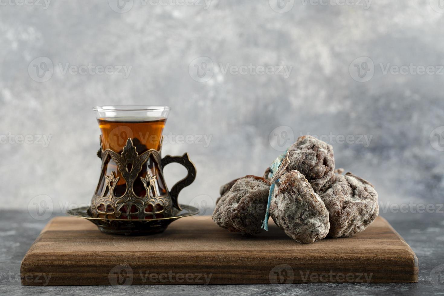 uma xícara de chá quente com caqui seco em uma placa de madeira foto