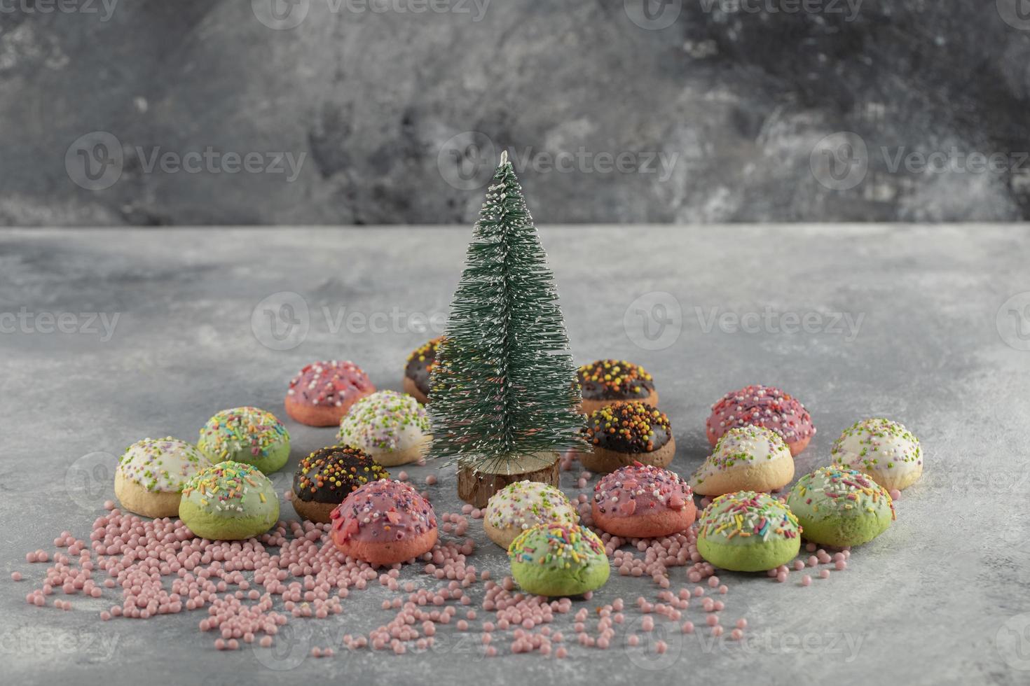 Rosquinhas pequenas doces e coloridas com granulado e um enfeite de natal foto