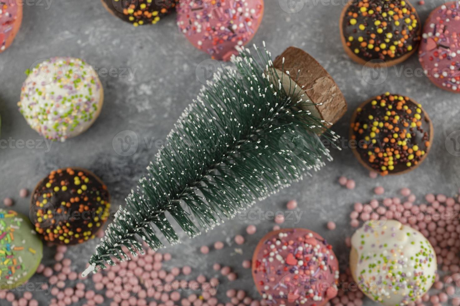 Rosquinhas pequenas doces e coloridas com granulado e um enfeite de natal foto