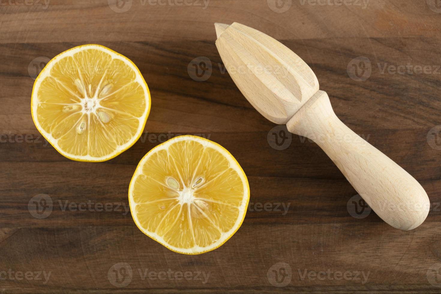 Limão fatiado com um alargador de madeira em uma mesa de madeira foto