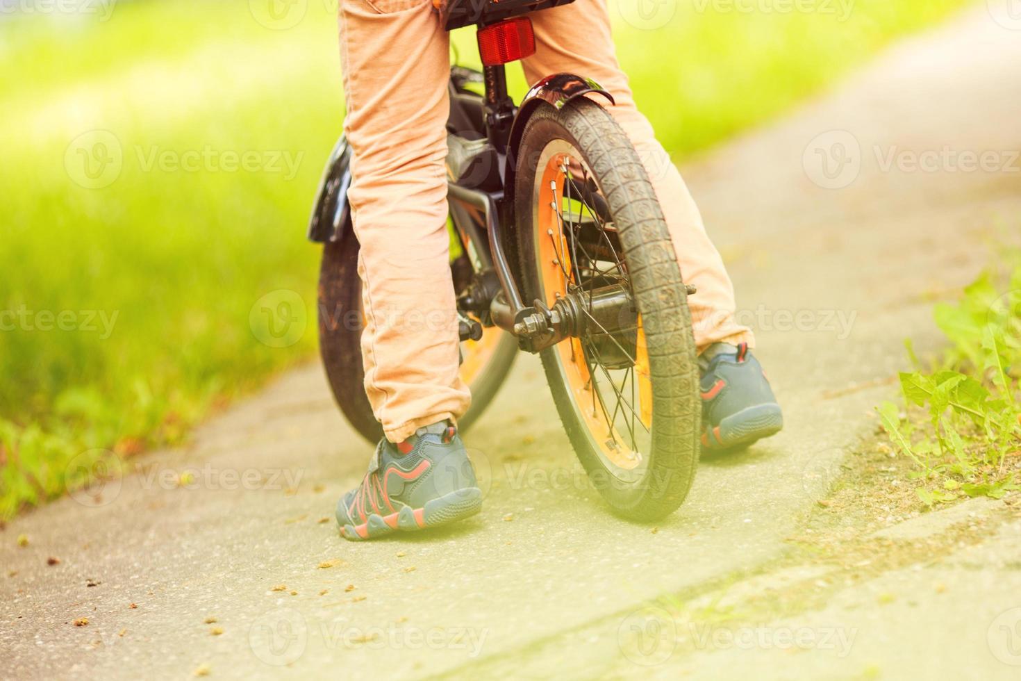 Garoto com uma bicicleta em a rua. roda do uma crianças bicicleta foto