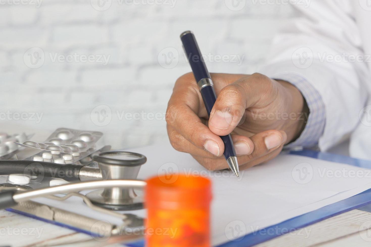 médico escrevendo receita na mesa da clínica foto