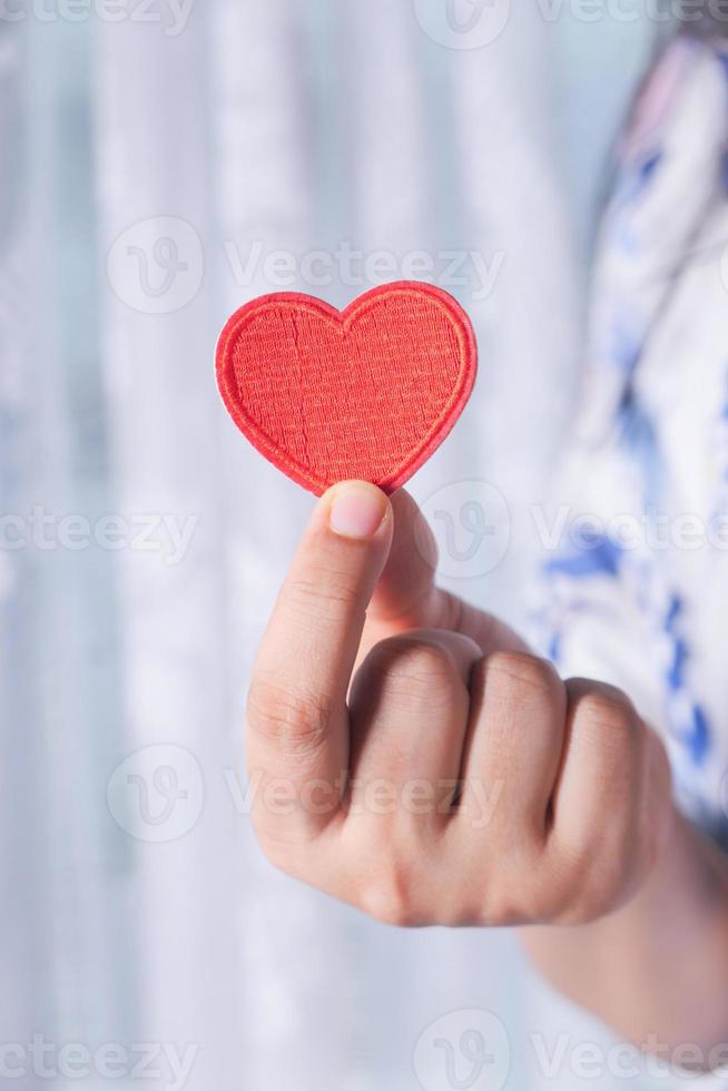 mão segurando um coração vermelho de brinquedo de perto foto