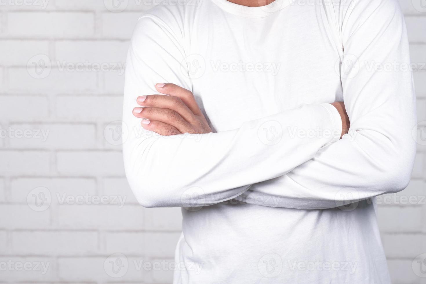 homem em pé com os braços cruzados em fundo neutro foto