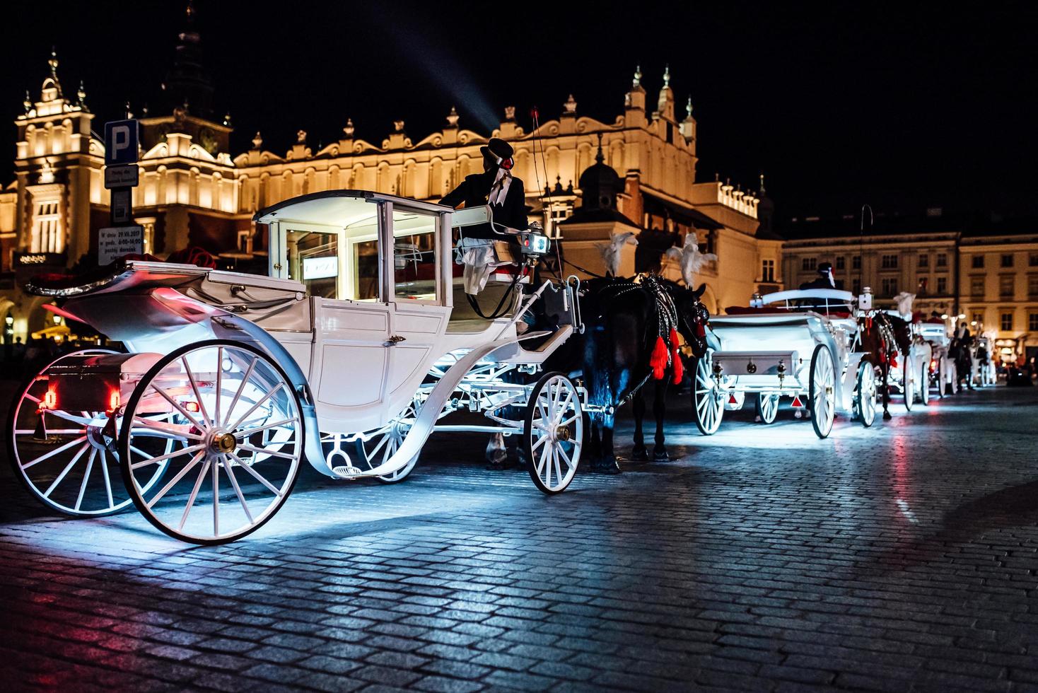 Cracóvia, Polônia 2017 - a antiga praça da noite em Cracóvia com carruagens puxadas por cavalos foto