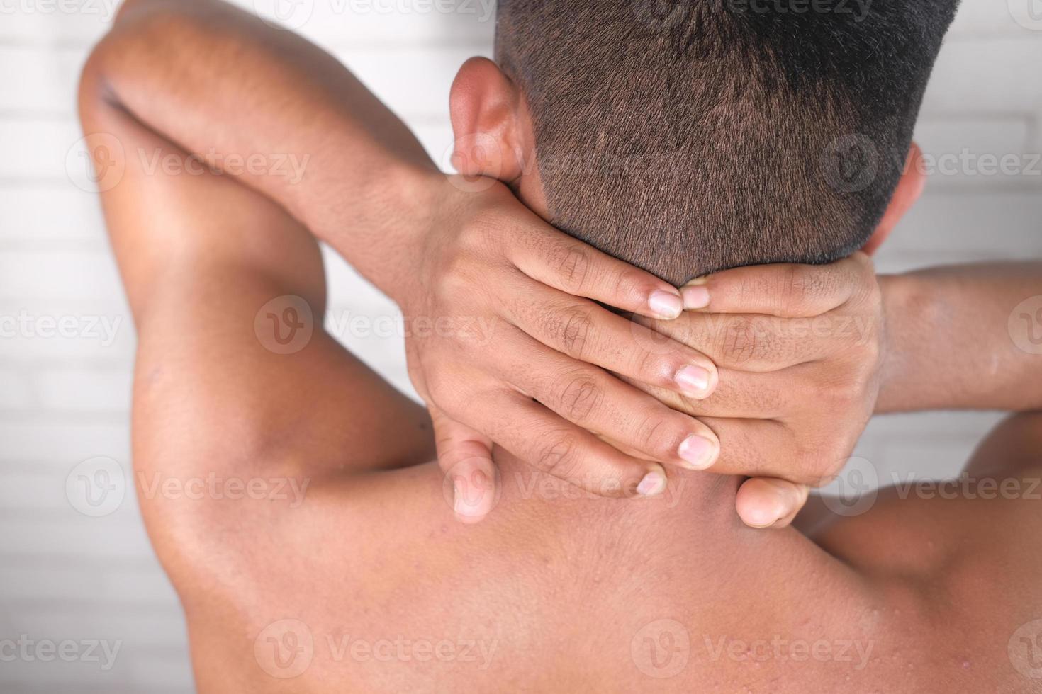 homem segurando o pescoço com dor por trás foto