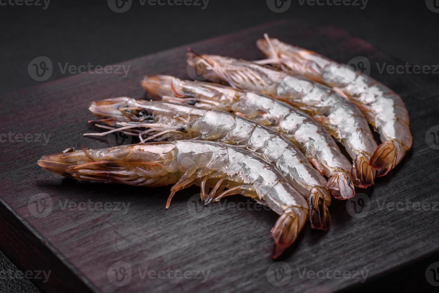 tigre camarão ou lagostim cru com especiarias e sal em uma de madeira corte borda foto